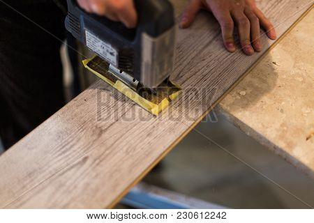 Contractor Cutting Laminate Flooring Lengthwise. Workers Cutting Laminate Flooring With Electric Saw