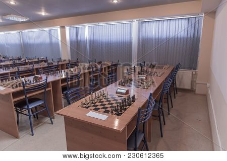Chess Club With Long Tables. Wooden Chess Board With Wooden Chess Pieces And Chess Clock.