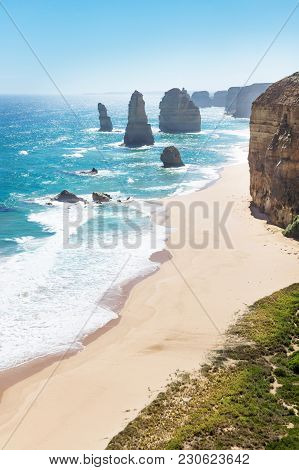 Twelve Apostels With Beach And Grass And Backlight At The Great Ocean Road Vertical, Victoria, Austr