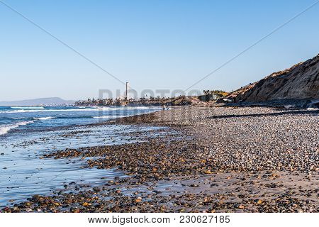 Stones Cover South Carlsbad State Beach In San Diego, California, With A Power Station Tower And Mou
