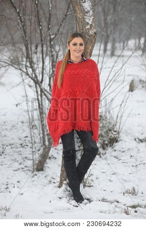Pretty Girl In Red Handmade Knitted Poncho With Fries. Standing Position In Park