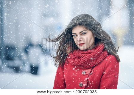 Winter. Girl Brunette Capless Smiles On The Background Of Snow. Close-up. Hair Develops. Wind And Sn