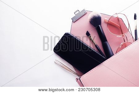 Flat lay of pink leather woman bag open out with cosmetics, acce