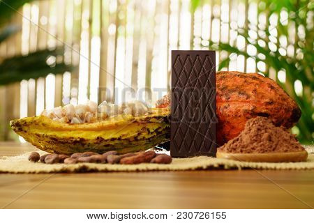 Bitter Chocolate Bar, Raw Cocoa Fruit, Cacao Beans And Cacao Butter On Wooden Table
