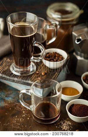 Coffee In Glass Cup, Coffee Beans, Ground Coffee And Brown Cane Sugar On Dark Background