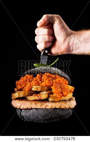 Italian Black Burger With Sausages Salamella , Potato And Vegetable Sauce. Stabbed The Knife And Mal