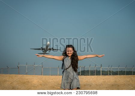 Aircraft Like A Bird. Jet Plane Takes Off On The Background Behind A Young Woman. Female Traveler Is