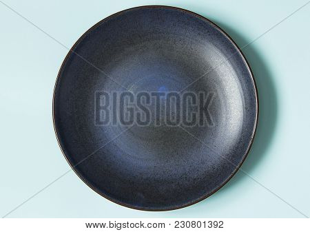 Empty Ceramic Round Plate On Background In Blue Pastel Colors. Top View With Copy Space.