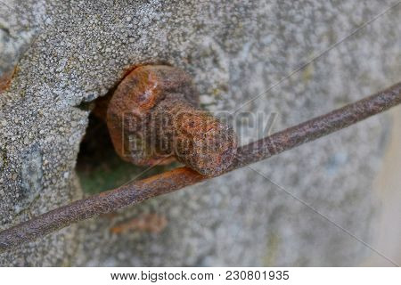 Rusty Nut And Screw With Wire In A Concrete Wall