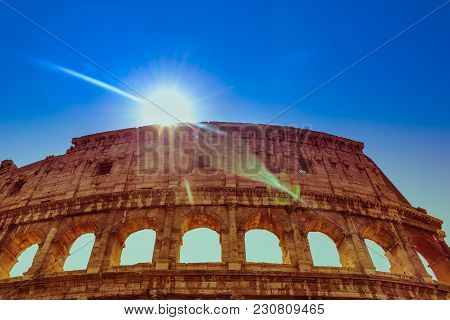 The Colosseum Or Coliseum Upper Part On A Clear Blue Sky Background With Sun Shining And Diagonal Ra