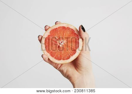 Close Up Hand Holding A Sliced Fresh Orange Fruit. Isolated On A Background With Copy Space For Text