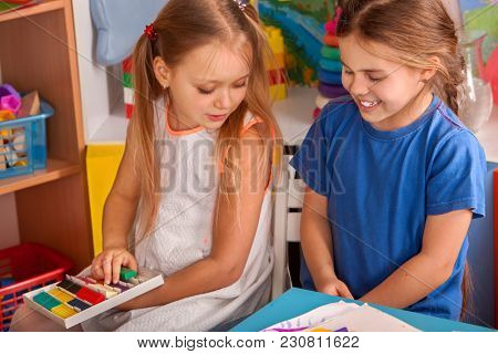 Plasticine modeling clay in children class. Teacher teaches kids together play dough and mold from plasticine in kindergarten or preschool. Group of four people. Teaching modeling of plasticine.