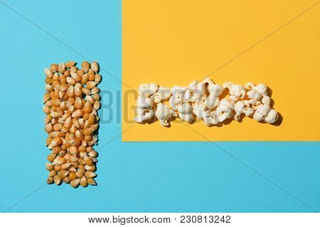 high angle view of a pile of unpopped corn and a pile of popcorn arranged in two perpendicular lines on a colorful yellow and blue background, with some blank space around them