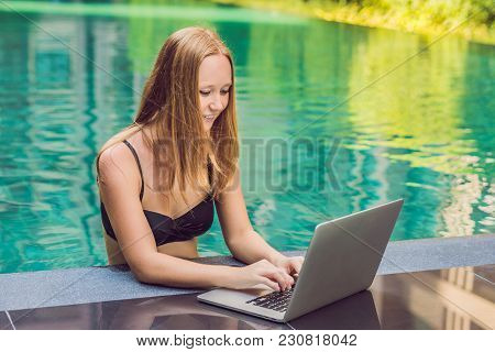 Young Female Freelancer Sitting Near The Pool With Her Laptop In The Hotel Browsing In Her Smartphon