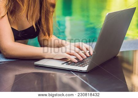 Young Female Freelancer Sitting Near The Pool With Her Laptop In The Hotel Browsing In Her Smartphon