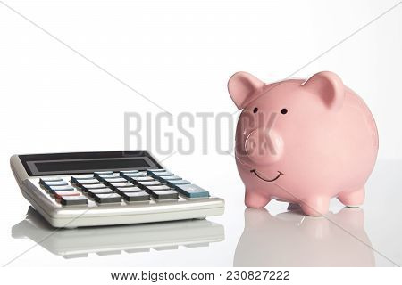 Calculator And Ceramic Pink Piggy Bank Isolated On White Background With Copy Space, Side View Close
