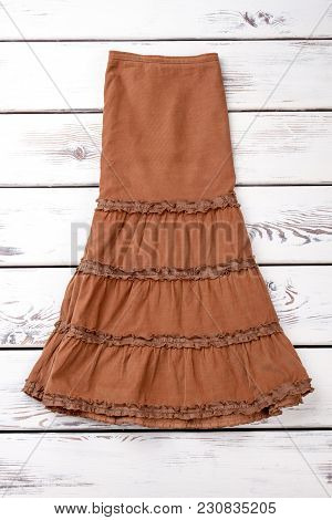Folded Brown Dress. White Wooden Desks Surface Background.