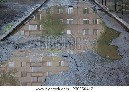 The Bad Asphalted Road With A Big Pothole Filled With Water. Dangerous Destroyed Roadbed. Mirror Ref