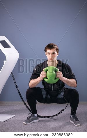 Fit Man In Ems Suit Training With Medecine Ball