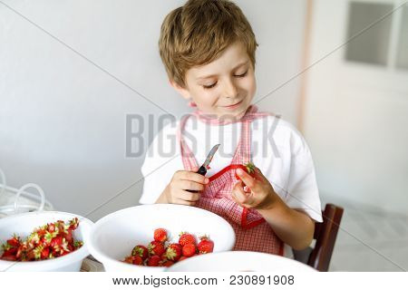 Little Blond Kid Boy Helping And Making Strawberry Jam In Summer. Funny Child Cleaning Berries And P