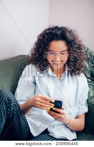Croped Photo Of Plasant Woman Surfing The Net On Phone On Sofa. Comfortable Sit. Wearing Glasses. Us
