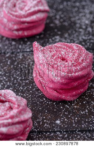 Close-up Meringues Sprinkled With Powdered Sugar. On Dark Background