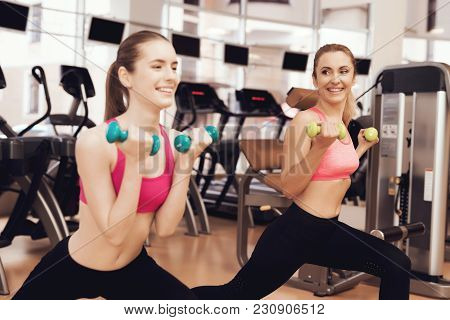 Mother And Daughter In Sportswear Doing Exercises With Dumbbells At The Gym. They Look Happy, Fashio