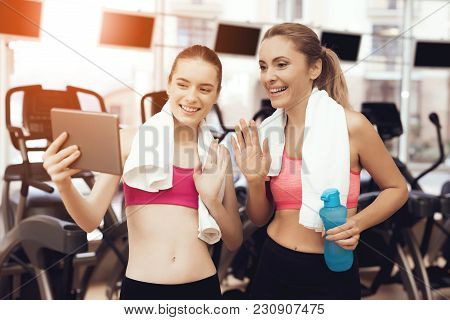 Mother And Daughter In Sportswear Using Tablet At The Gym. They Look Happy, Fashionable And Fit.
