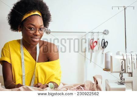 Smiling African Seamstress Looking At Camera With Sewing Machine