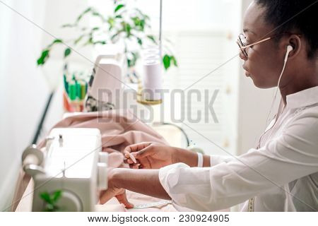 African Female Sewing Fabric With Needle At Seamstress Workplace