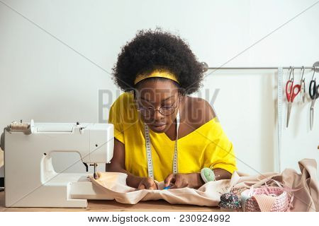 African Female Sewing Fabric With Needle At Seamstress Workplace