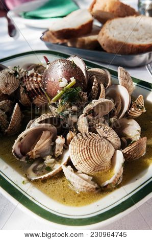 Sea Food Dish With Shells, Chard And Garlic In White Wine Sauce With Bread In Background