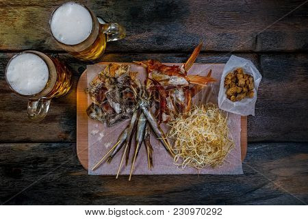 Assorted Beer Snacks With Cheese Chechil, Dried Fish And Crackers, Served On The Rustic Cutting Boar