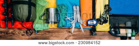 Top View Of Equipment For Hiking And Travel On Wooden Background . Items Include Trekking Pole, Mult