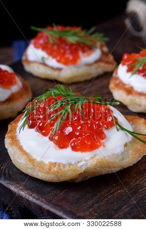 Pancakes With Red Caviar And Cream Cheese Topped With Dill On The Wooden Board