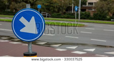 This Way Roadsign. Road Sign One Way, Blue And Round, White Color Arrow Pointing Direction Right And