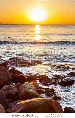 Scenic Rocky Beach Cala Violina Landscape At The Sunset. The Sun Is Going Down Behind The Horizon. T