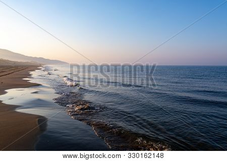 Unidentified Man Jogging In Orange Sportswear On Sandy Beach On Sinrise Over Sea Or Ocean, Seascape