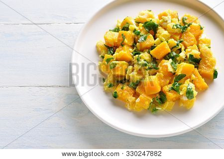 Close Up Of Stir-fried Pumpkin With Eggs On Plate Over Light Wooden Background.
