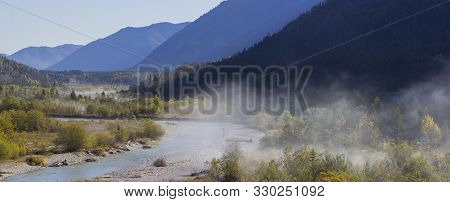 Foggy Autumn Trees At The River In The Isar Valley, At Vorderriss With Parts Of The Pfetter Kopf, Th