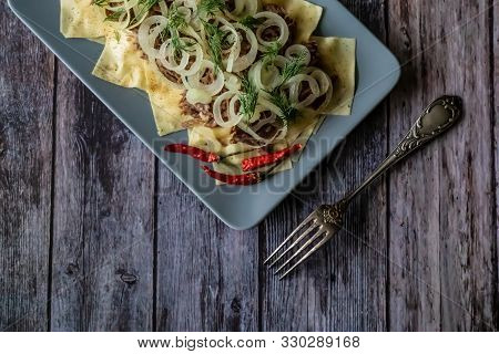 Beshbarmak Is A National Kyrgyz Dish - Square Pasta With Boiled Meat And Onions. On Wooden Backgroun