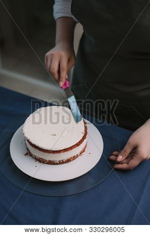 The Confectioner Levels The Cream On The Cake. The Cook Creates A Cake, Collects It And Covers It Wi