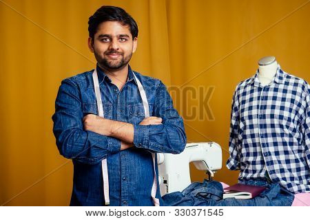 Handsome Indian Tailor Man In A Stylish Shirt Working With Dreen Jeans Cotton Textile At Home Worksh