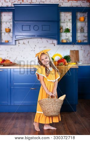 Little Girl Holds Basket Of Bread. Little Girl Holds Basket With Bread On Background Of Kitchen. Bas