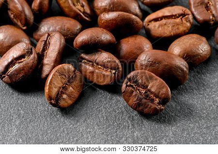 Scattering Of Roasted Coffee Beans Close-up On Gray Background