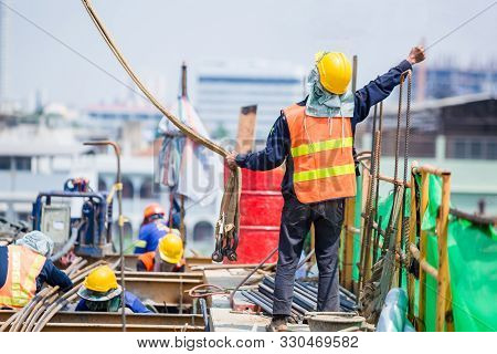 Construction Team Working At Height Site. Construction Workers Raising Hands To Signal Construction