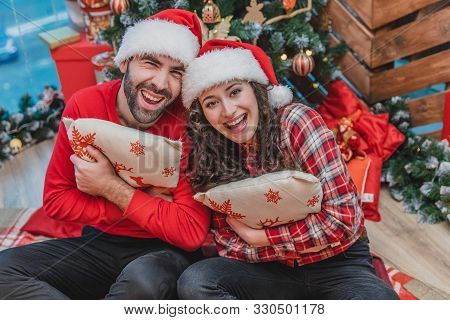 Cheerful Women And Men In Red Having Fun While Lights Are Sparkling On The Christmas Tree.