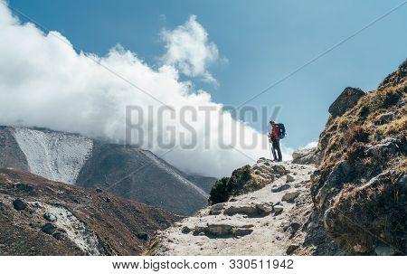 Hiker Man Silhouette On Clouds Background Standing On Path Going Over The Imja Khola Valley And Enjo