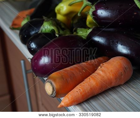 Still Life Of Vegetables Blue Eggplant, Carrots, Sweet Peppers Lying On The Table.