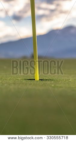 Vertical Frame Focus On Golf Course Yellow Flagstick And Hole In The Middle Of Putting Green